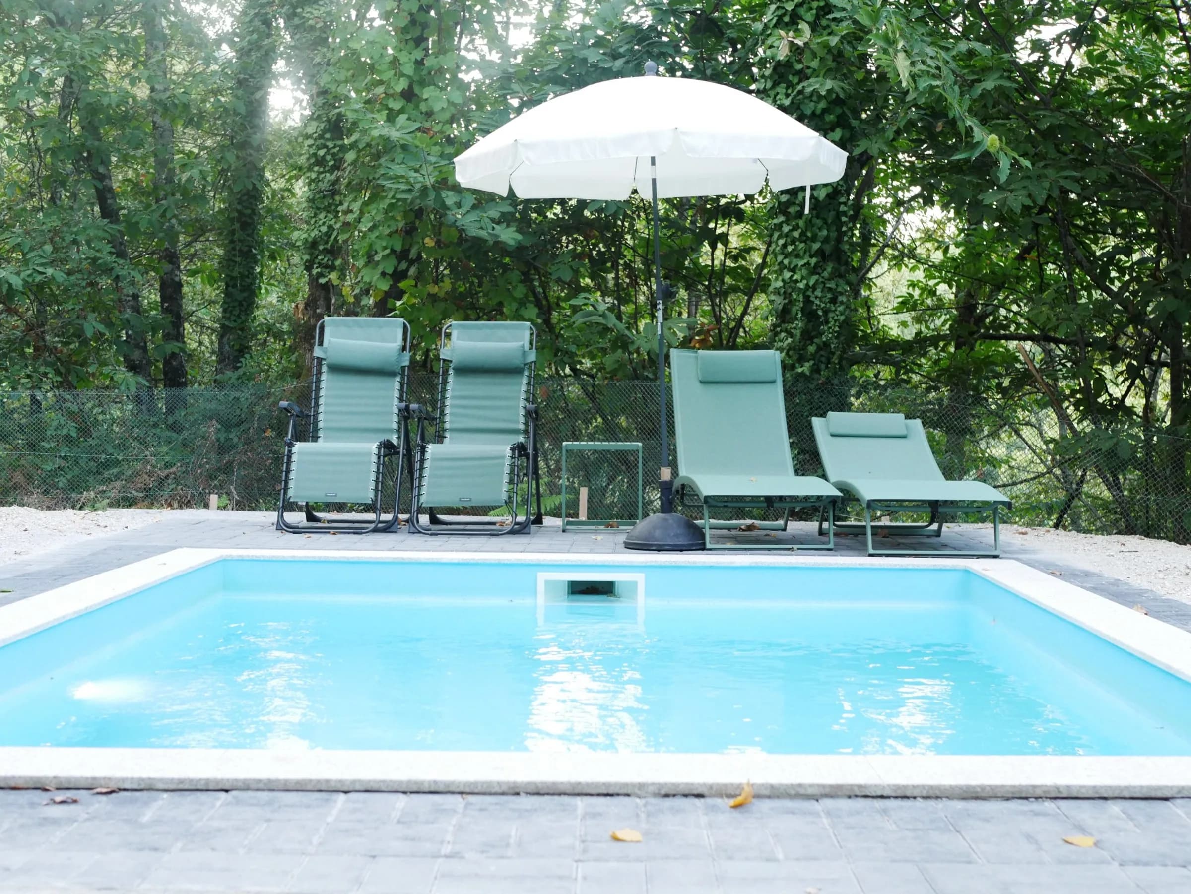 Piscina da Cabana das Aveleiras com espreguiçadeiras e chapéu de sol